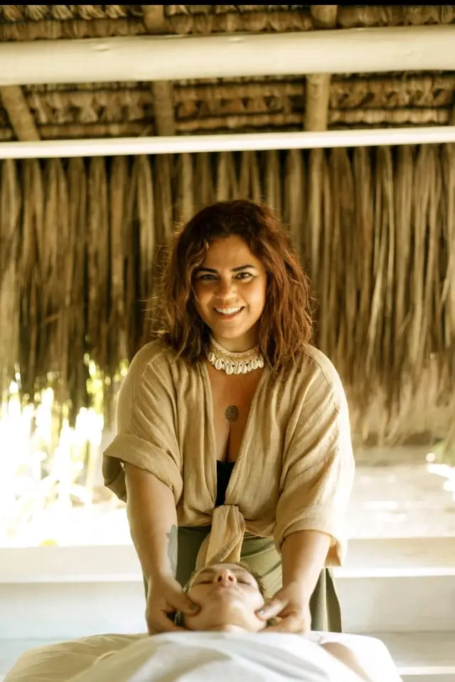 Érika Americano sorrindo, com as mãos sobre a maca